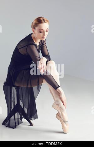 Dancer woman in black dress posing assis sur une chaise Banque D'Images