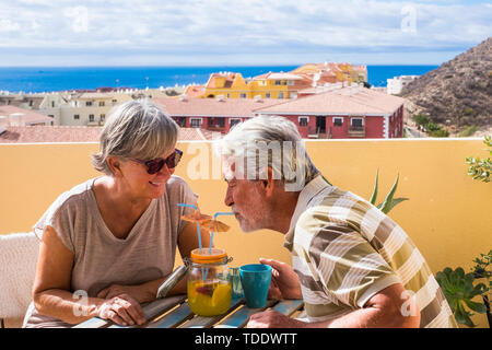 Vie des retraités avec happy senior couple having fun ensemble à la maison sur la terrasse de l'alcool même verre de jus de fruit - une ville et Banque D'Images