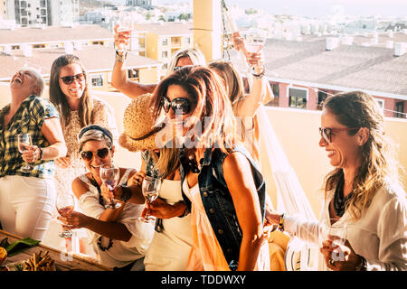 Groupe de jeunes personnes gaies et les femmes âgées ont du plaisir ensemble fête avec vin et ayant beaucoup de plaisir en terrasse extérieure avec vue sur la ville - HAP Banque D'Images