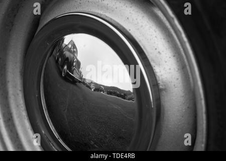 Reflet d'une voiture classique dans un autre chapeau de roue de voiture classique. Banque D'Images