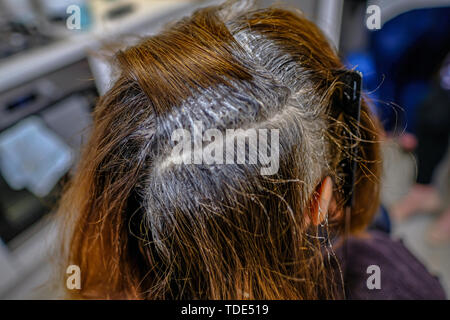 Gros plan de cheveux foncés ayant les racines de couleur. Une séparation avec la teinte appliquée. Banque D'Images