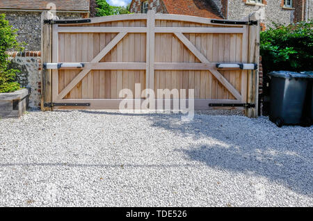 Entrée en bois grande hauteur portails électriques qui sont fermées. À la recherche de l'intérieur avec une voie privée en pierre au premier plan. Banque D'Images