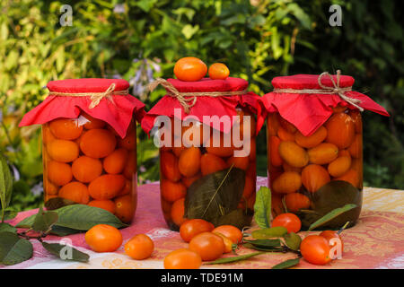 Tomates cerises marinées en pots sur une table dans le jardin Banque D'Images