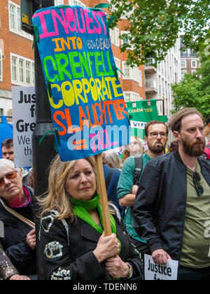 Londres, Royaume-Uni. 15 juin 2019. Une femme dans un manteau nacré est titulaire d'une affiche appelant à une enquête et pour les gens à être emprisonné plus de Grenfell en dehors du Ministère du logement, des communautés et des Gouvernements locaux sur la justice pour la marche de solidarité de Grenfell, jour après le deuxième anniversaire de l'incendie dans la tour de Grenfell, dont 72 personnes sont mortes, ainsi que la justice4Grenfell, l'événement a été soutenu par les militants de la sécurité du logement et de la construction et par branches de l'Union des pompiers de partout dans le Royaume-Uni. Peter Marshall/Alamy Live News Banque D'Images