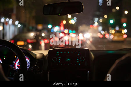 La conduite dans New York la nuit. Vue de l'intérieur de cabine de taxi dans la circulation. Plan rapproché sur la planche de bord. Bokeh couleurs lights out de la fenêtre Banque D'Images