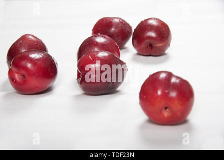 Prune rouge posé nonchalamment sur fond blanc Banque D'Images