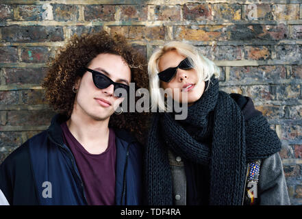 Young couple Camden Town en face d'un mur de briques typiques de Londres Banque D'Images