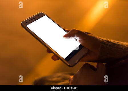 Girl holding un smartphone avec un écran blanc dans la nuit Banque D'Images