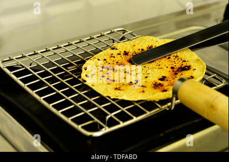 Une Indienne Papad snack-être rôti sur une cuisinière à gaz. Banque D'Images