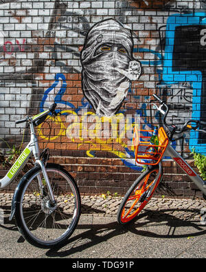 Lidl Location & Mobike location vélo garé à côté de l'écriture graffiti-couverts mur du cimetière de Baruther Strasse, Kreuzberg-Berlin Banque D'Images