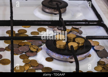 Flammes bleues de la combustion de gaz naturel d'une cuisinière à gaz sur un arrière-plan de la monnaie. Banque D'Images