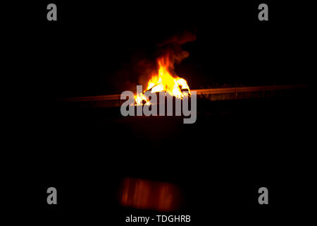 Véhicule en feu sur la route dans la nuit Banque D'Images