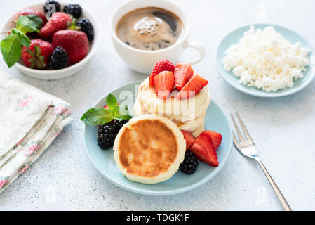 Crêpes au fromage cottage Syrniki avec fraises et tasse de café sur la table. La cuisine ukrainienne, russe Banque D'Images