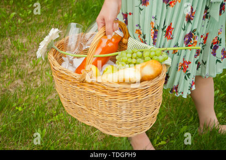 Femme dans une robe sur l'aire de pique-nique panier pique-nique tient dans une main. Banque D'Images