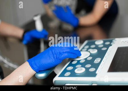 Un vétérinaire ne une échographie de l'œil du chien dans le bureau. Homme main du médecin sur un appareil à échographie close-up. Clinique vétérinaire l'arrière-plan. Banque D'Images