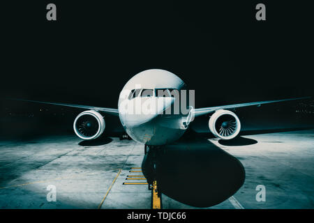 Avion Avion garé au terminal vue depuis le poste de pilotage avant du fuselage, sur la piste de nuit Banque D'Images
