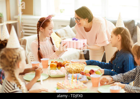 High angle portrait of smiling mother cadeau d'anniversaire à sa fille pendant party, copy space Banque D'Images