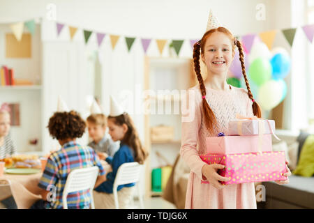 Portrait of happy red haired girl holding gift boxes posing during Birthday party avec des amis, copy space Banque D'Images