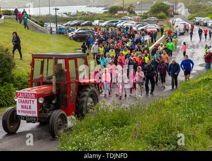 Tracteur Massey Ferguson rouge à la tête d'une foule de gens sur un organisme de bienfaisance à pied Banque D'Images