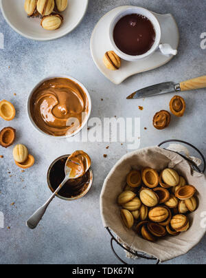 Cookies Noix dans un panier de dulce de leche dans un bol et tasse de thé sur fond gris Banque D'Images