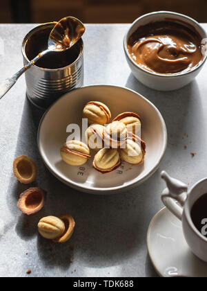 Cookies Noix dans un panier de dulce de leche dans un bol et tasse de thé sur fond gris Banque D'Images