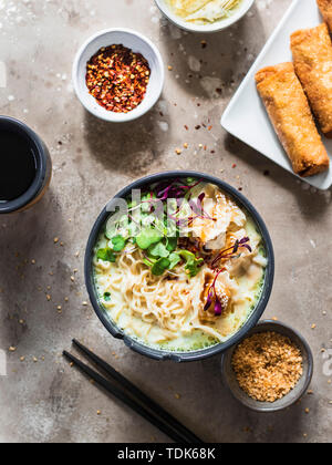 Service de table asiatique : la soupe de nouilles ramen avec des boulettes de porc, pâtés impériaux et les artichauts. Banque D'Images