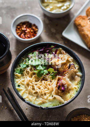 Service de table asiatique : la soupe de nouilles ramen avec des boulettes de porc, pâtés impériaux et les artichauts. Banque D'Images