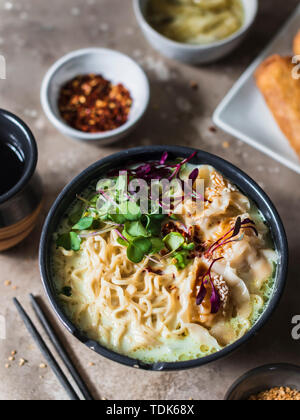 Service de table asiatique : la soupe de nouilles ramen avec des boulettes de porc, pâtés impériaux et les artichauts. Banque D'Images