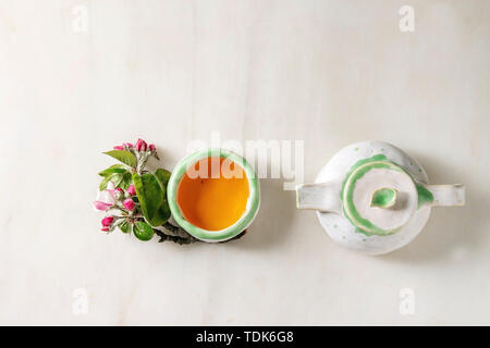 Fait main artisanat théière et tasse en céramique avec du thé chaud décoré par cherry blossom printemps branches sur fond de marbre blanc. Mise à plat, de l'espace Banque D'Images