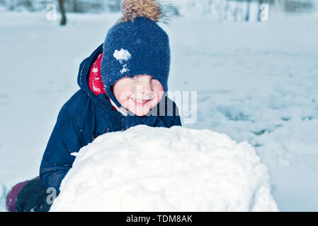Portrait d'hiver d'un petit garçon heureux. kid rit et sourit. enfant fait un bonhomme. émotion bonheur en vacances Banque D'Images