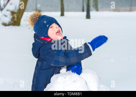 Petit garçon en agitant sa main dans la neige. l'enfant est en cours de lecture. kid sculpte snowman Banque D'Images