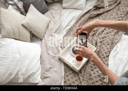 Woman taking shot du bac avec la nourriture on bed Banque D'Images