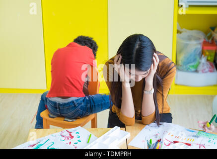 Obtenir de l'enseignant de tête avec deux enfants naughty en classe à l'école maternelle. Banque D'Images