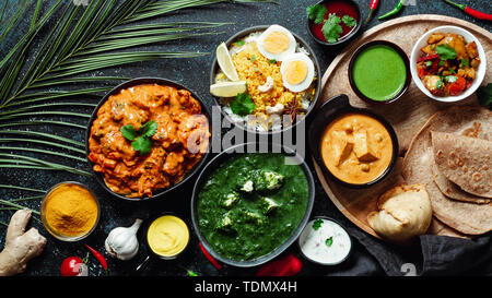 Des plats de cuisine indienne : tikka masala, paneer, samosa, chapati, chutney, épices. La nourriture indienne sur fond sombre. Assortiment repas indien haut afficher ou mettre à plat. L'espace de copie pour le texte. Banque D'Images