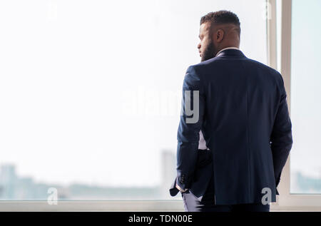Succès african businessman looking through window à des bâtiments de la ville Banque D'Images