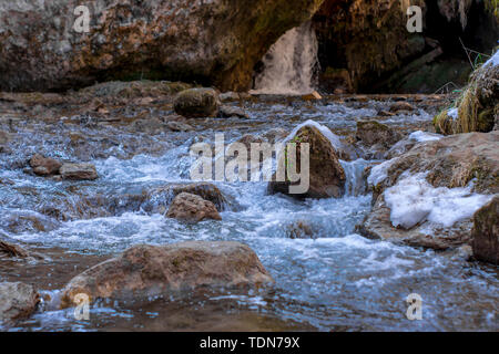 Cold Mountain River s'écoule entre les pierres avec de la neige et de la glace, selective focus, une cascade en arrière-plan, Karachay-Cherkess République. Banque D'Images
