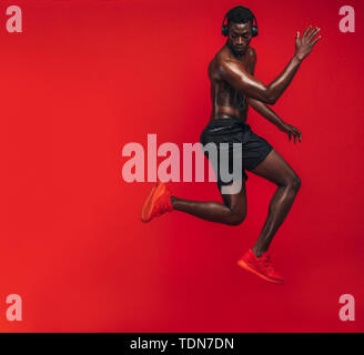 African American man avec corps musclé exerçant sur fond rouge. Tiré d'un bon jeune homme faisant de l'exercice dans Studio. Banque D'Images