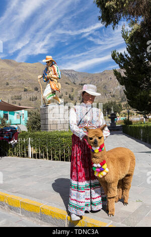 Femme en costume traditionnel avec un lama pose dans la plaza de la maca, Canyon de Colca, Pérou, Amérique du Sud, Banque D'Images