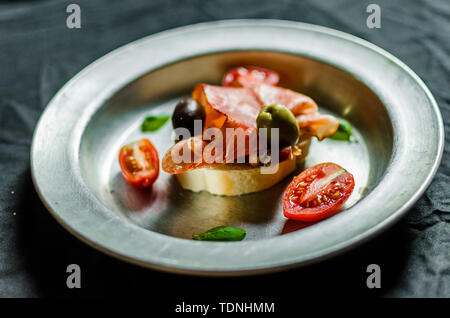 Tapas espagnoles avec sandwich jambon jambon, olives, tomates, basilic et Banque D'Images