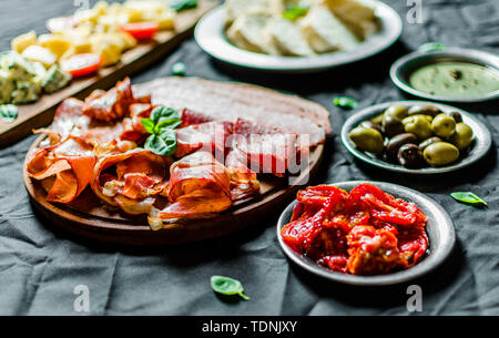 La viande froide et du fromage italien antipasti charcuterie plateau sur fond noir Banque D'Images