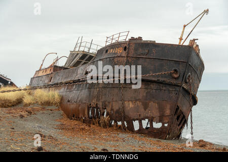 Rusty cargo échoué sur la rive avec des chaînes en la maintenant enfoncée Banque D'Images