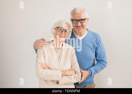 Affectionate couple senior dans smart casualwear vous regarde en se tenant debout en face de la caméra dans l'isolement Banque D'Images