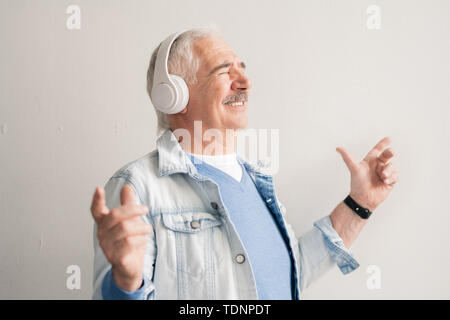 Cheerful senior man with headphones écouter sa musique préférée et d'en profiter dans l'isolement Banque D'Images