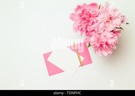 Télévision créative d'enveloppe en papier rose avec une plume d'or, un bouquet de pivoines rose isolé sur fond blanc Banque D'Images