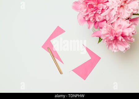 Télévision jeter Vue de dessus de l'enveloppe de papier rose avec une plume d'or, un bouquet de pivoines rose isolé sur fond blanc Banque D'Images