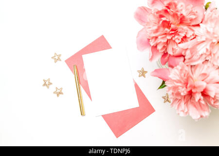 Les créatifs d'enveloppe en papier rose avec une plume d'or, un bouquet de pivoines corail isolé sur fond blanc Banque D'Images