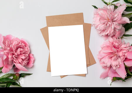 La mise en page d'accueil minimaliste carte avec fleurs de pivoines rose, enveloppe pour la couture, la floraison, la mise à plat, vue du dessus Banque D'Images