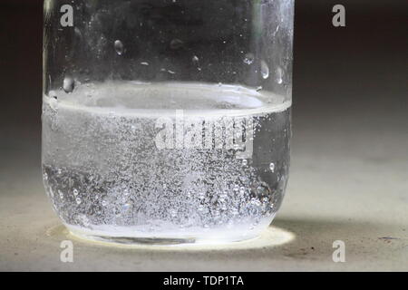 Libre d'une réaction du vinaigre et du bicarbonate de soude qui se passe dans le fond d'un bocal en verre liquide ; clear avec bulles Banque D'Images