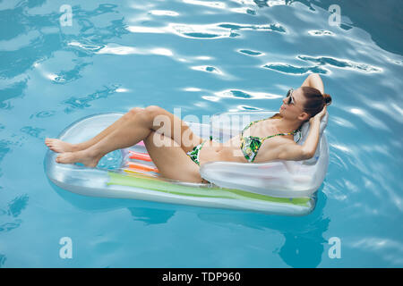 Woman in bikini détente sur un tube gonflable dans la piscine Banque D'Images