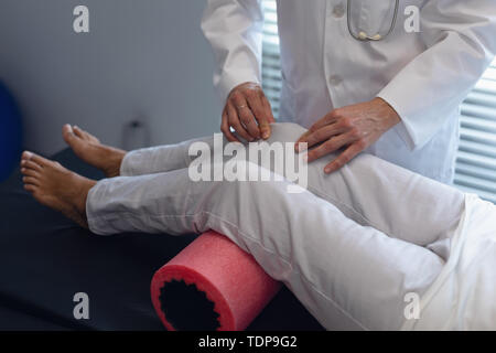 Femme médecin à l'aide de rouleau en mousse sur la jambe du patient à l'hôpital Banque D'Images